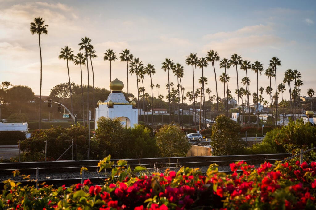 The gold-domed Self-Realization Fellowship temple with palm trees and railway tracks at sunset