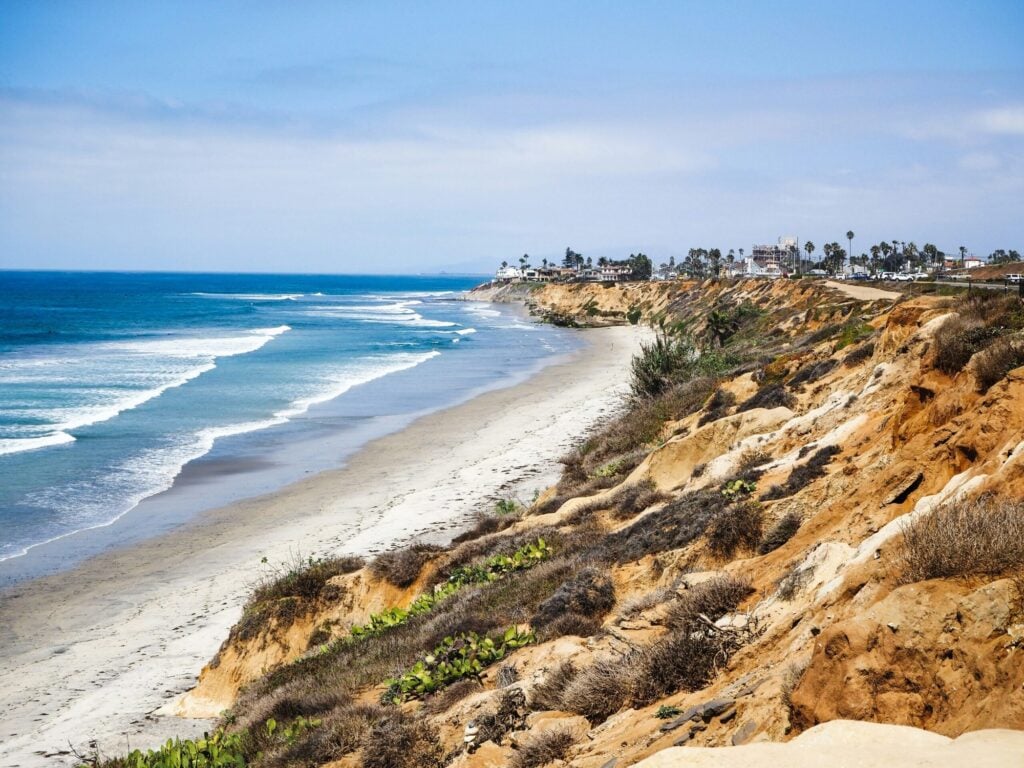 Sandstone bluffs above the beach on the Carlsbad coast, with waves rolling in and homes along the cliff top