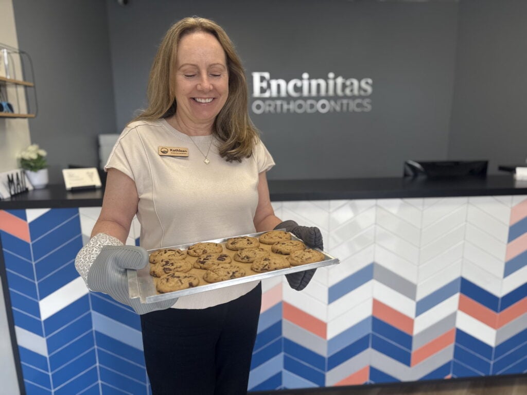 An Encinitas Orthodontics team member holding a tray of fresh-baked cookies at the front desk